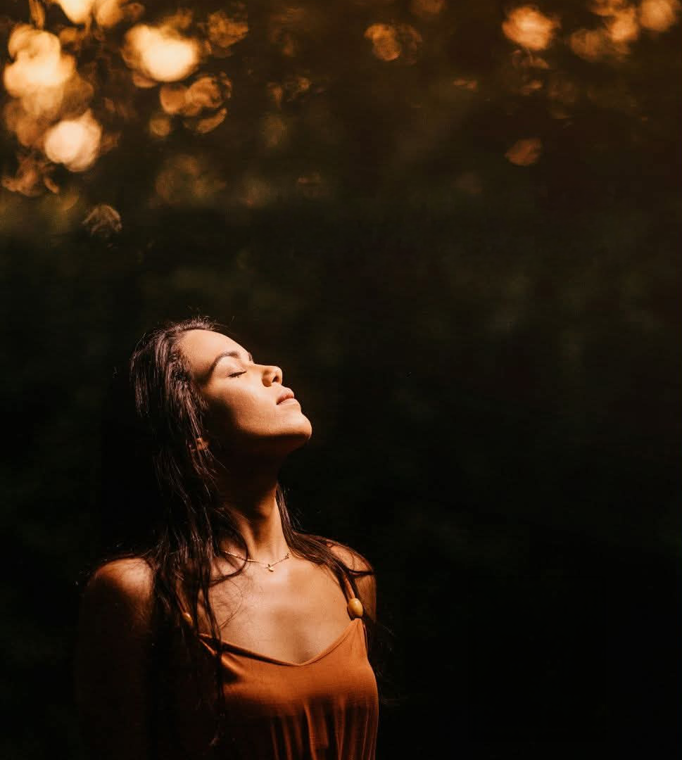 Woman standing peacefully in a sunlit meadow